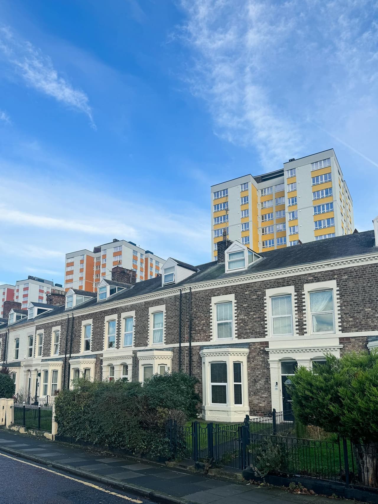 Vibrant street view of terraced houses with colourful tower blocks in Newcastle upon Tyne, England.